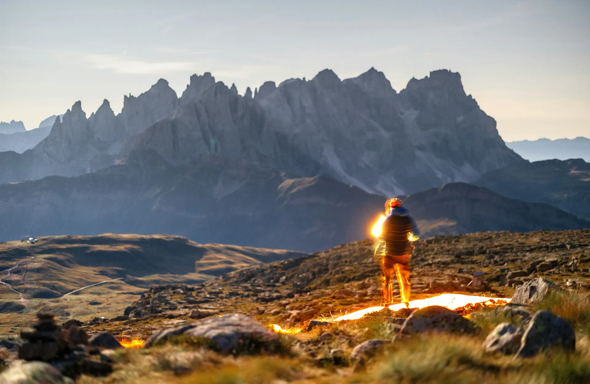 Hiker tracing light across a mountain ridge